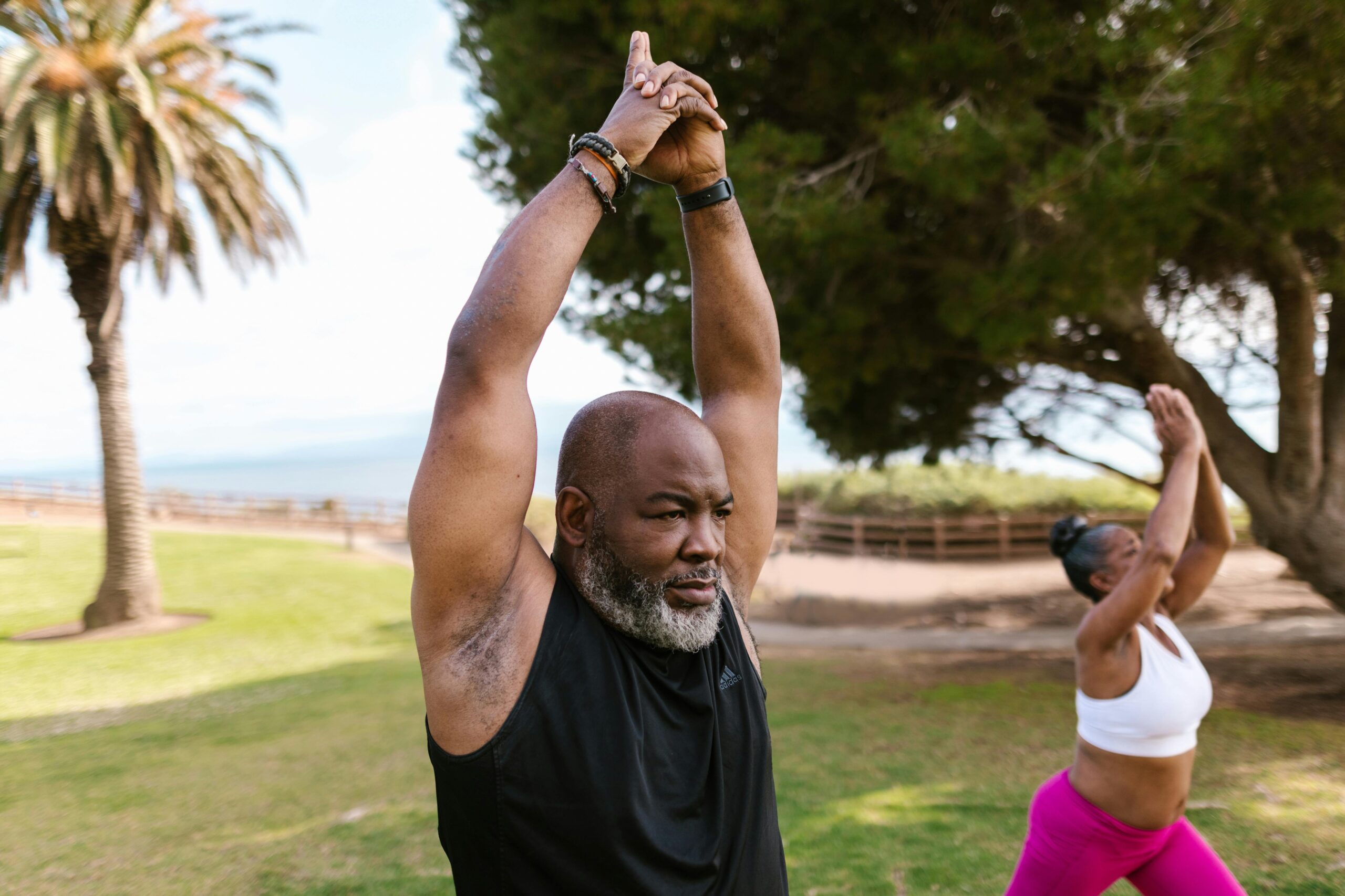 Senior adults engaging in outdoor yoga practice in a park, promoting wellness and relaxation.